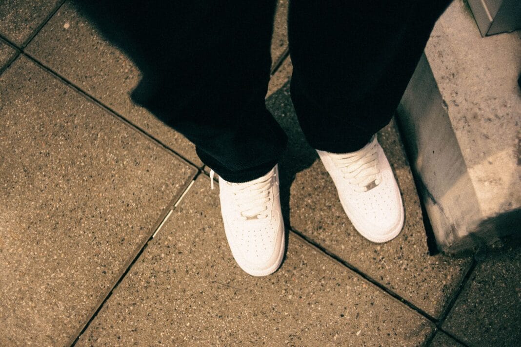 Białe sneakersy na miejskim chodniku w stylu ulicznym z góry