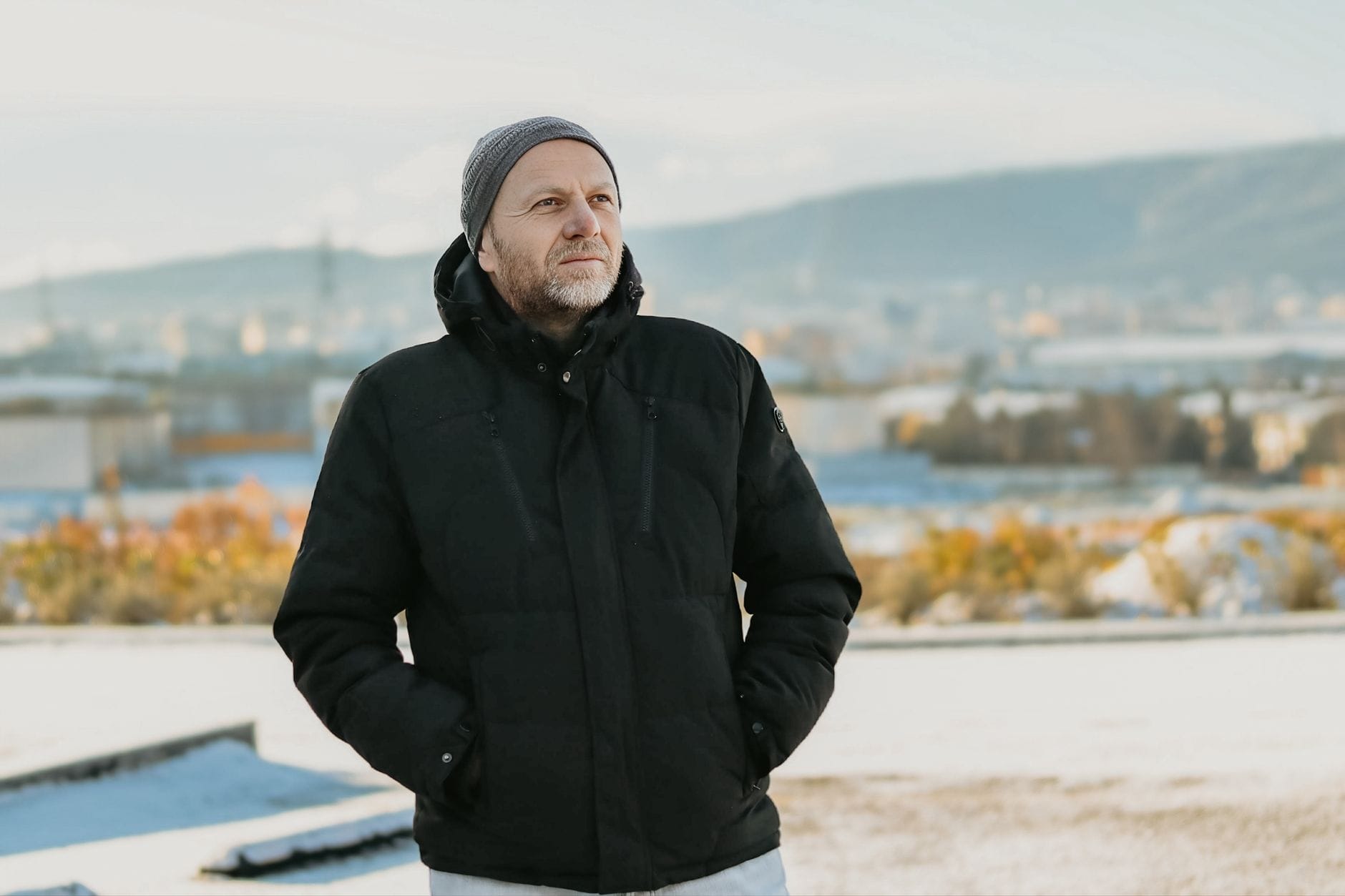 Mężczyzna po czterdziestce w czarnej kurtce i czapce zimą